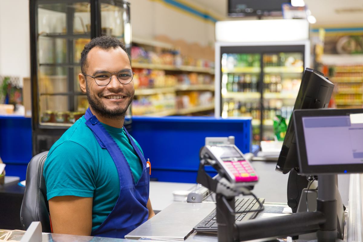 Cajero atendiendo con una sonrisa en el mostrador